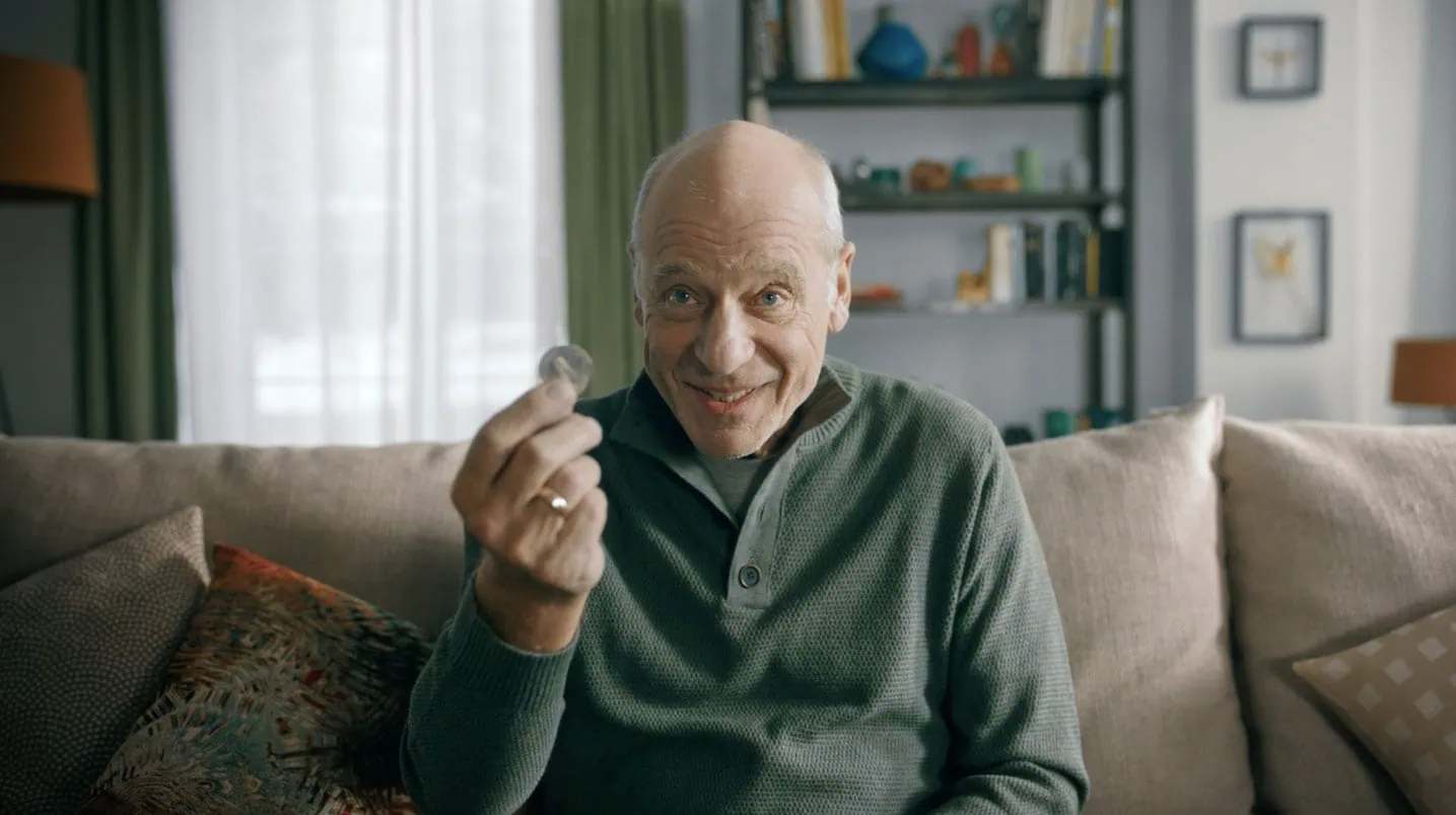 Ein älterer Mann mit einer Münze im UBS-Werbespot Sparen – Opa.